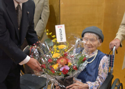 In September 2023, aged 109, being presented with a bouquet by Prefectural Assembly Speaker Tatsuya Tokunaga. (Source: Nishinippon Shimbun)