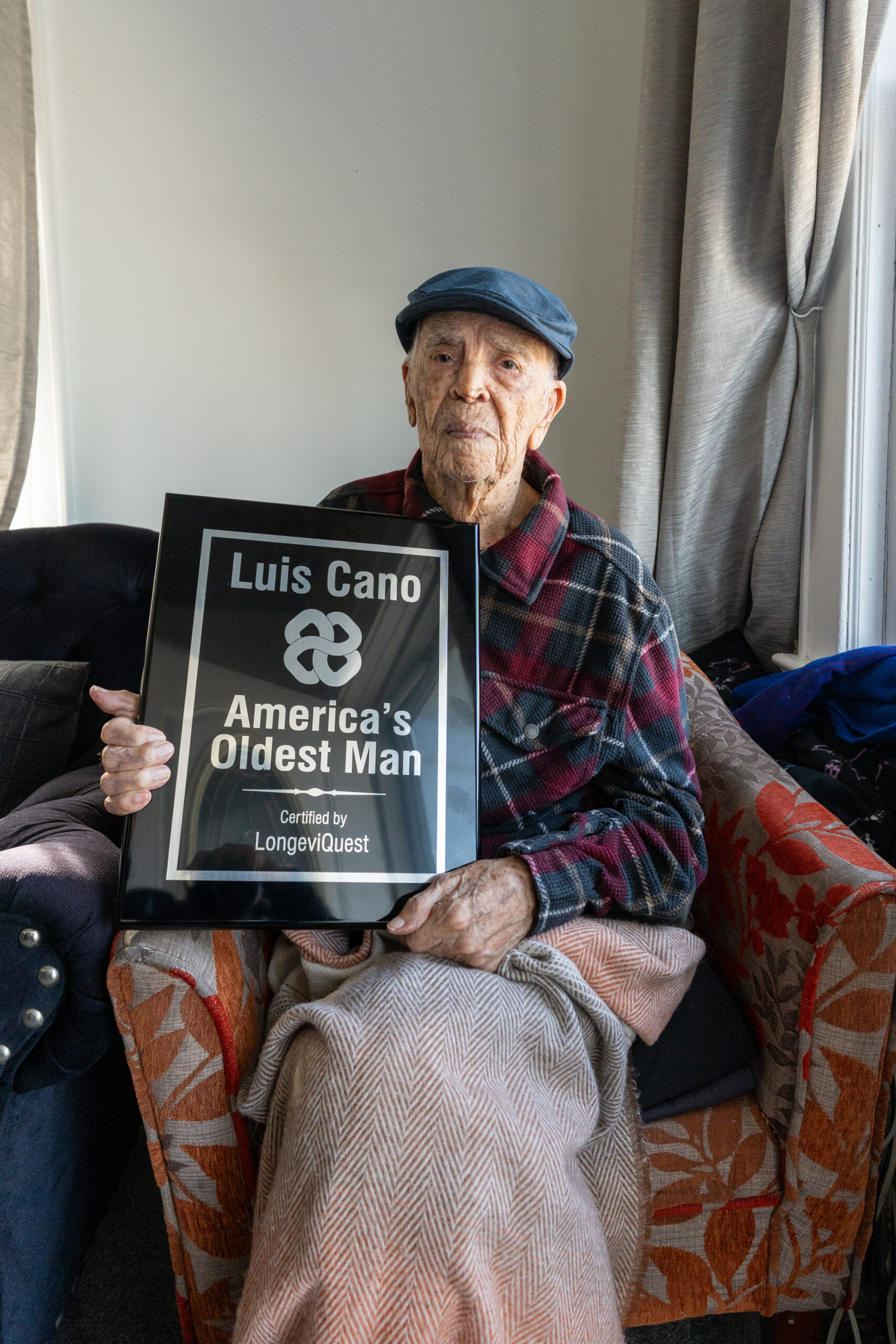 Luis Cano, America's oldest known living man, holding his LongeviQuest trophy.