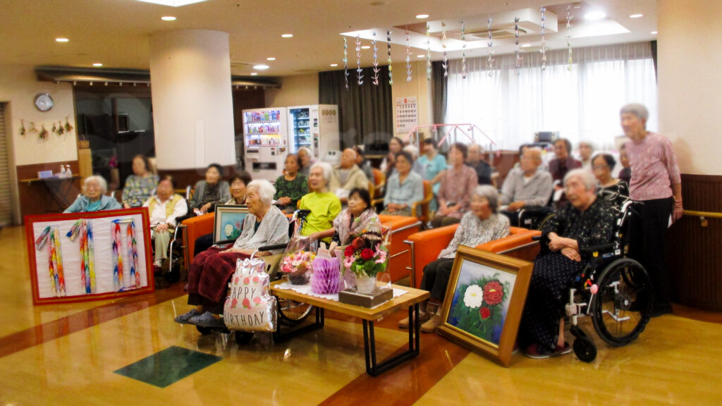 Kinue Sakamoto celebrates her 110th birthday with fellow residents and staff members at her nursing home on 4 June 2026. One of her peony paintings was displayed during the celebration. (Photo provided by the nursing home)