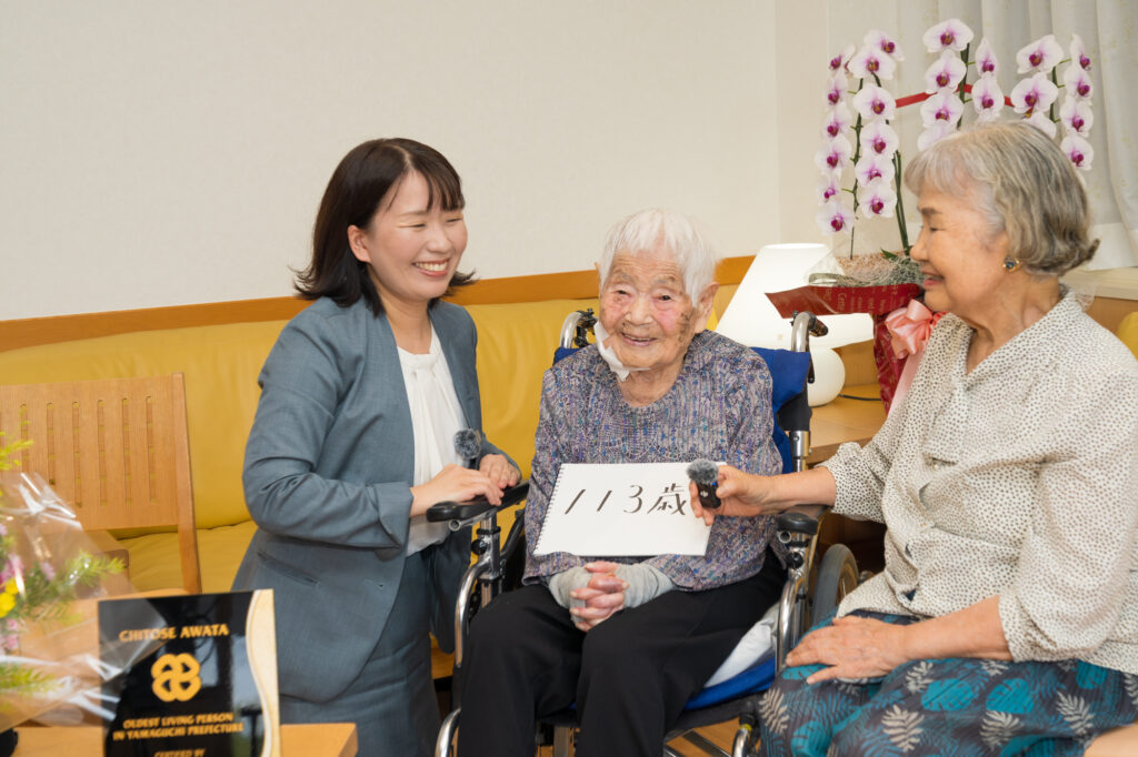 Mrs. Chitose Awata (粟田千年), 113, with her daughter, Mrs. Nobuko Kondo (近藤伸子), and LongeviQuest&rsquo;s Yumi Yamamoto.